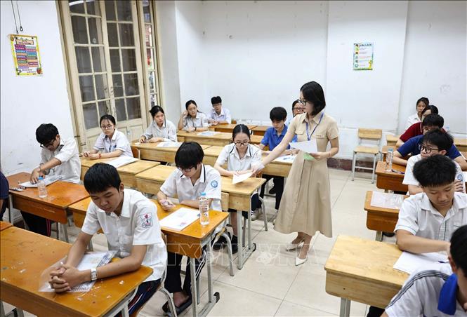 Giám thị tại điểm thi Trường THPT Trần Phú - Hoàn Kiếm phát giấy nháp cho các thí sinh. Ảnh: Thanh Tùng - TTXVN
